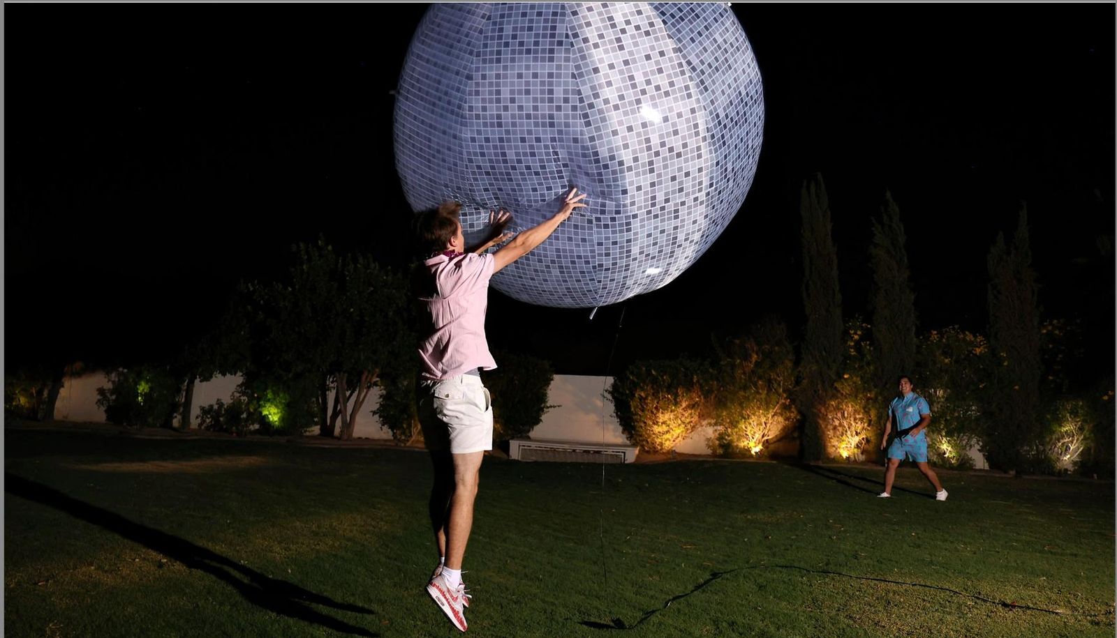 A guest beside a glowing moon sculpture on the lawn
