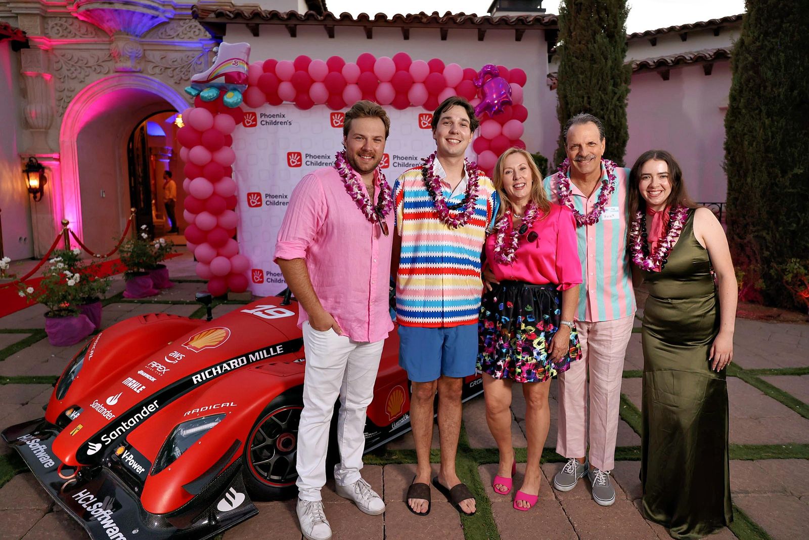 Guests at the Barbie Land Party beside the Radical SR3 race car used for the toy drive